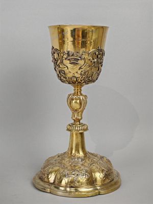 une coupe en or richement décorée, posée sur un socle, sur fond blanc