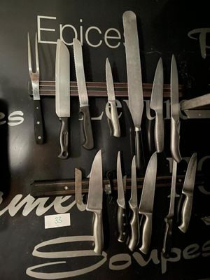 beaucoup de couteaux accrochés au mur de la cuisine