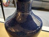 un vase bleu posé sur une table devant une fenêtre