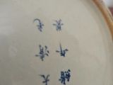 a white vase with blue writing on it sitting on a table