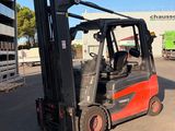 a red forklift truck parked in front of a building