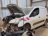 une camionnette blanche dont le capot est cassé, garée dans un garage