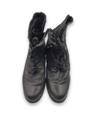 une paire de bottes en cuir noir à lacets posées sur une surface blanche