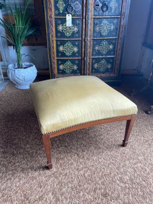 a yellow foot stool sitting on top of a carpeted floor next to a cabinet