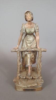 une statue représentant une femme assise sur une chaise