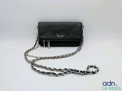 le petit sac à main noir est posé sur une surface blanche