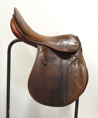 a brown saddle on a black stand against a white wall