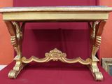 une table dorée avec un plateau en marbre, recouverte d'une nappe rouge