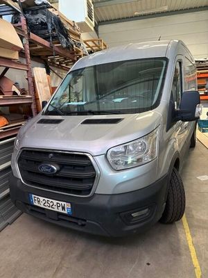 La camionnette argentée est garée dans l'entrepôt, devant une pile de cartons.