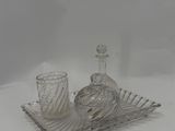 a glass tray with a bottle and a glass cup on it