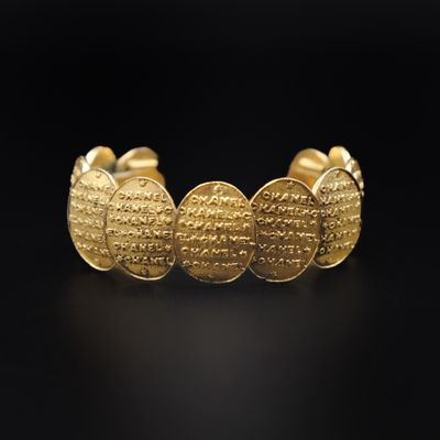 un bracelet manchette en or orné d'un motif de pièce de monnaie