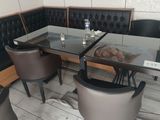 tables and chairs in a restaurant with a glass table and black leather chairs