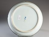 a white plate with a blue flower on it on a stand