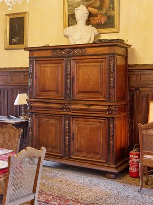 une salle à manger avec une table et des chaises, et un buste d'homme accroché au mur