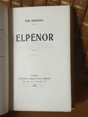 un livre ouvert posé sur une table, à côté d'une pile de livres