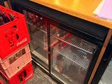 bottles of soda are stacked on top of each other in front of a refrigerator