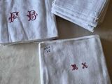 three white towels with red letters on them sitting on top of a bed