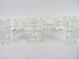 four clear glass goblets sitting on top of a white table