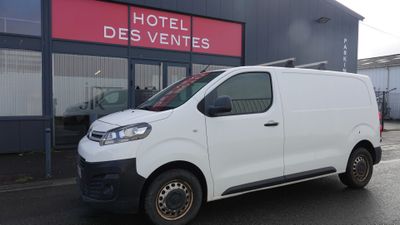 une camionnette blanche garée devant un bâtiment dans un parking