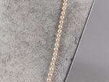 a white pearl necklace on a mannequin neck with a gold clasp