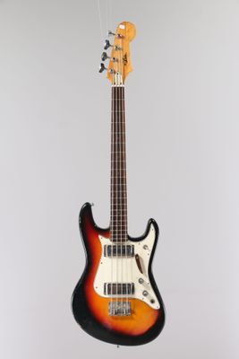 an electric bass guitar hanging from a string on a wall