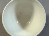 a white bowl sitting on a table with a shadow of a person in the bowl