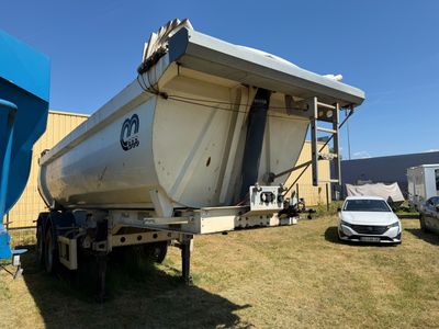 un grand bateau blanc sur une remorque, garé dans l'herbe