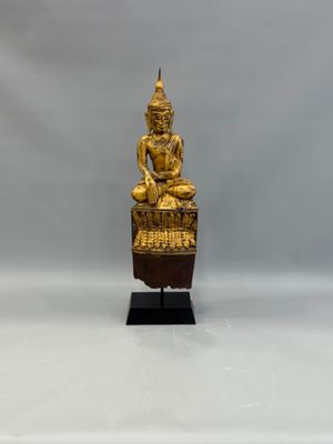 a gold statue of a seated buddha on a wooden stand