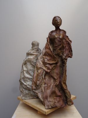 sculpture représentant une femme et un homme assis sur une estrade en bois