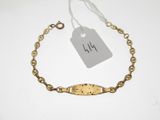 a close up of a gold bracelet with a tag on it