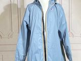 un imperméable bleu posé sur un mannequin devant un mur blanc