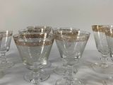 six wine glasses with gold rims are lined up on a white table
