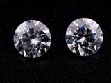 two round brilliant cut diamonds on a black surface