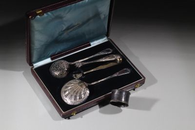 un service d'argenterie dans un coffret posé sur une table