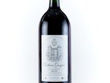 the bottle of red wine is sitting on a white surface