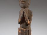 an old wooden statue of a man with his hands crossed