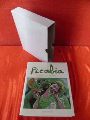 the book is sitting on a red cloth next to a white box