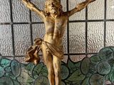 a statue of jesus on a cross in front of a stained glass window