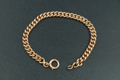 gros plan d'un bracelet en chaîne en or sur une surface noire