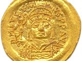 a close up of a gold coin with a face on it