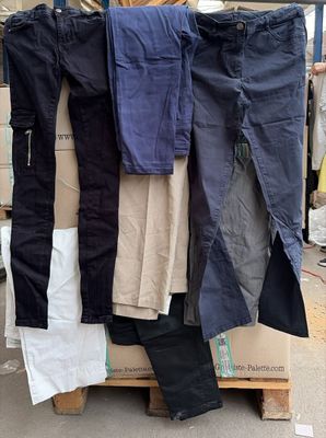 de nombreux pantalons de différentes couleurs posés sur une palette dans la rue