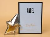 un flacon de parfum en forme d'ange à côté d'une boîte ornée d'une étoile