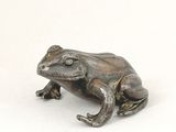 statue of a frog sitting on a rock on a white surface