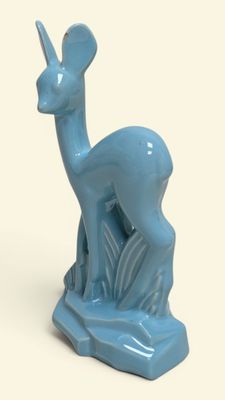 a small blue statue of a deer on a white surface