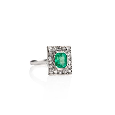 a close up of a ring with a green stone surrounded by white diamonds