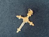 une croix en or surmontée d'une couronne, posée sur un tissu bleu