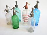 quatre bouteilles en verre de couleurs différentes, munies d'un bec verseur en métal