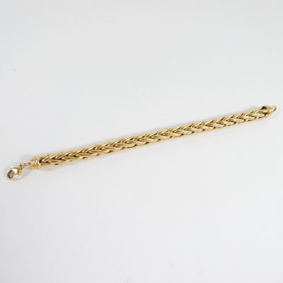 gros plan d'un bracelet en or sur une surface blanche