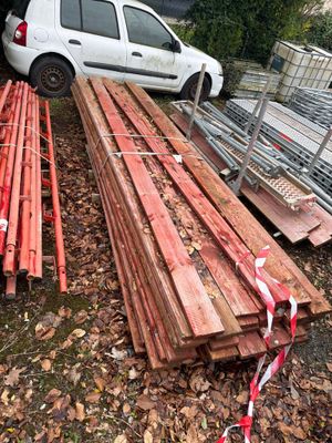 une voiture blanche garée à côté d'un tas de bois