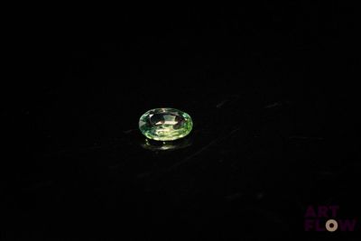 a close up of a green diamond on a black surface